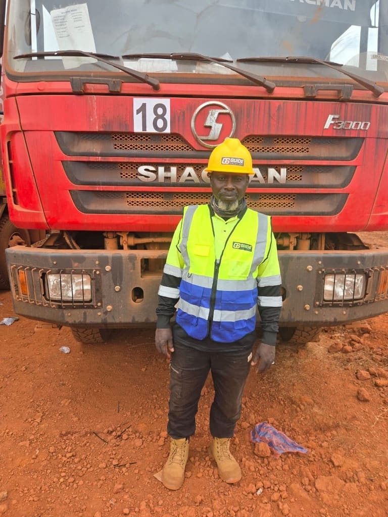 Agent en gilet haute visibilité et casque jaune devant le camion-benne rouge numéro 18