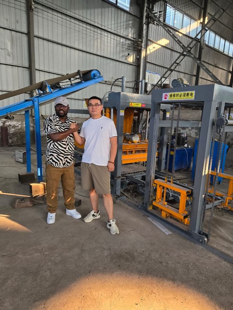 Deux hommes devant une machine de fabrication de blocs de béton dans un atelier