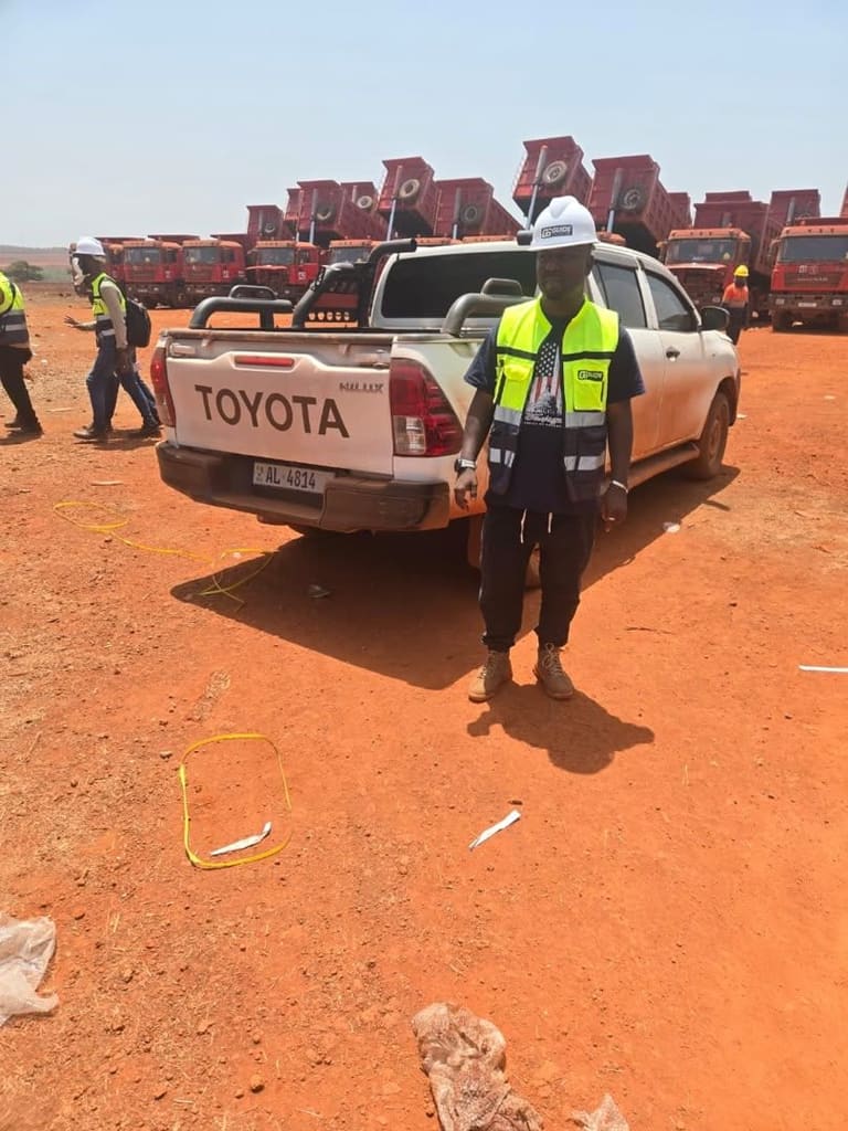 Homme en gilet haute visibilité près d'un pick-up, flotte de camions rouges en arrière-plan