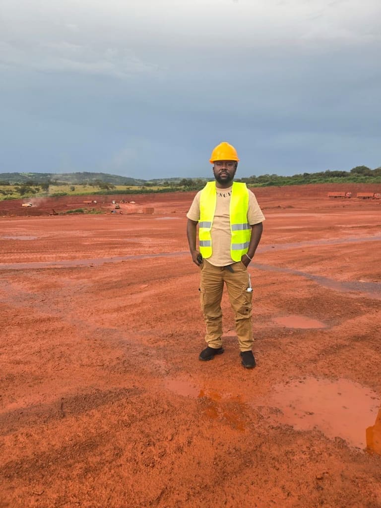 Technicien en gilet haute visibilité sur une vaste plateforme de terrassement en latérite