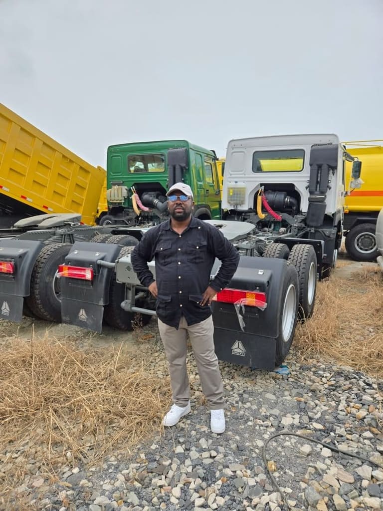 Homme devant des tracteurs routiers neufs sur un parc gravillonné
